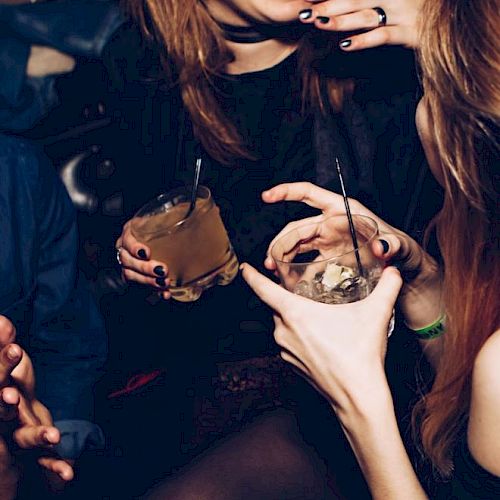 People are enjoying drinks and laughter in a lively setting, highlighting a social and festive atmosphere.